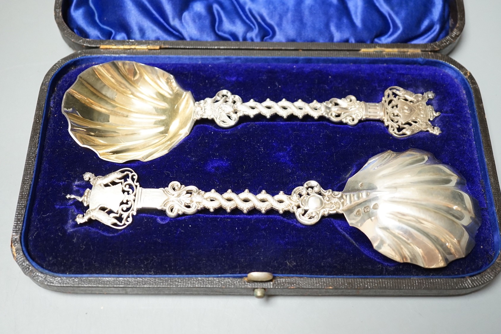 A cased pair of ornate late Victorian silver serving spoons, with entwined stems and terminals modelled as the crest of The Salter's Company, Francis Higgins III, London, 1894, 19.5cm, 5oz.